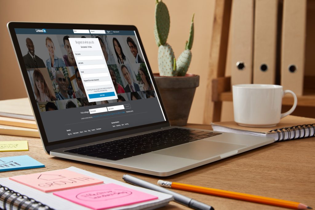 A lapton on a desk with the homepage of LinkedIn on it